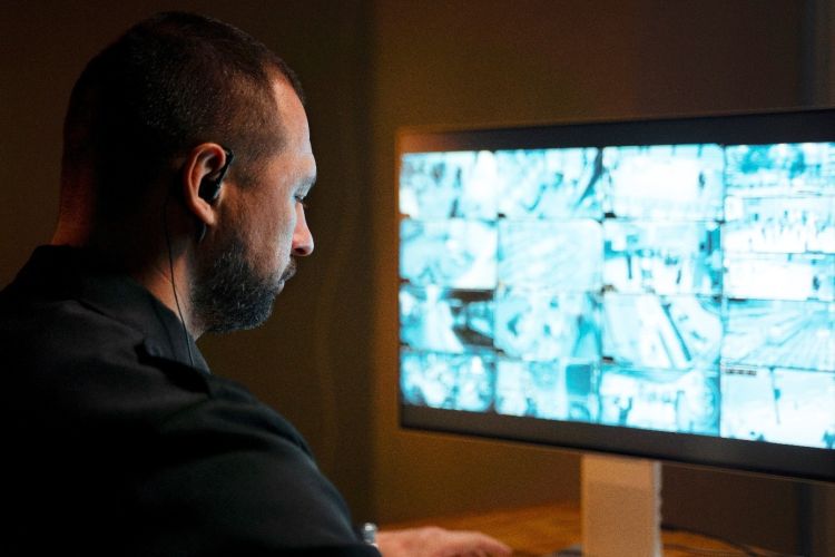 Zdjęcie przedstawia mężczyznę oraz monitor na którym widać monitoring wizyjny.