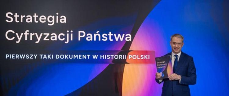 Obraz przedstawia grafikę promującą dokument „Strategia Cyfryzacji Państwa”. Po lewej stronie widoczny jest tytuł oraz hasło „Pierwszy taki dokument w historii Polski”, a po prawej mężczyzna w garniturze prezentuje egzemplarz publikacji. Grafika nawiązuje do działań państwa związanych z rozwojem cyfryzacji i transformacją cyfrową administracji publicznej.