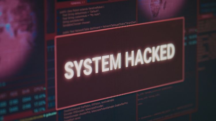 SYSTEM HACKED Obraz przedstawia ekran komputera z dużym komunikatem „SYSTEM HACKED”, sugerującym skuteczny cyberatak lub przejęcie systemu. W tle widoczne są okna z kodem i interfejsem systemowym w czerwono-czarnej kolorystyce, podkreślające temat zagrożeń cyberbezpieczeństwa. Grafika symbolizuje naruszenie bezpieczeństwa systemów informatycznych oraz ryzyko ataków hakerskich.